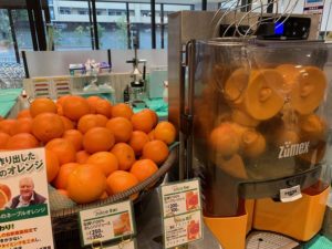 ジュースバーの店頭にはたくさんのオレンジの隣にフレッシュなオレンジジュースを搾るマシンがあります